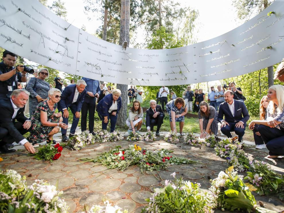 El alcalde de Oslo, Raymond Johansen (i), el príncipe heredero Haakon (4i) y la princesa Mette Marit (2i), entre otras personalidades, en una ofrenda floral en la isla de Utoya, uno de los escenarios de los atentados de hace diez años.