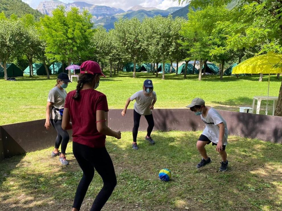 Un grupo de niños jugando con la mascarilla puesta en el campamento de YMCA en Oto (Broto).