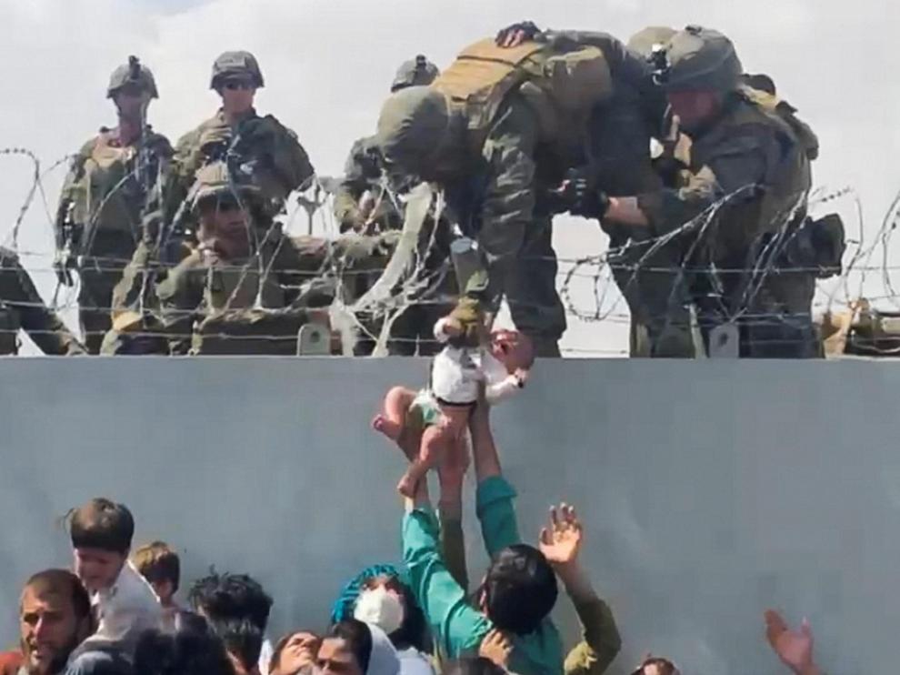 Una familia, presa de la desesperación, entrega a su bebé a los soldados estadounidenses en el muro del aeropuerto.
