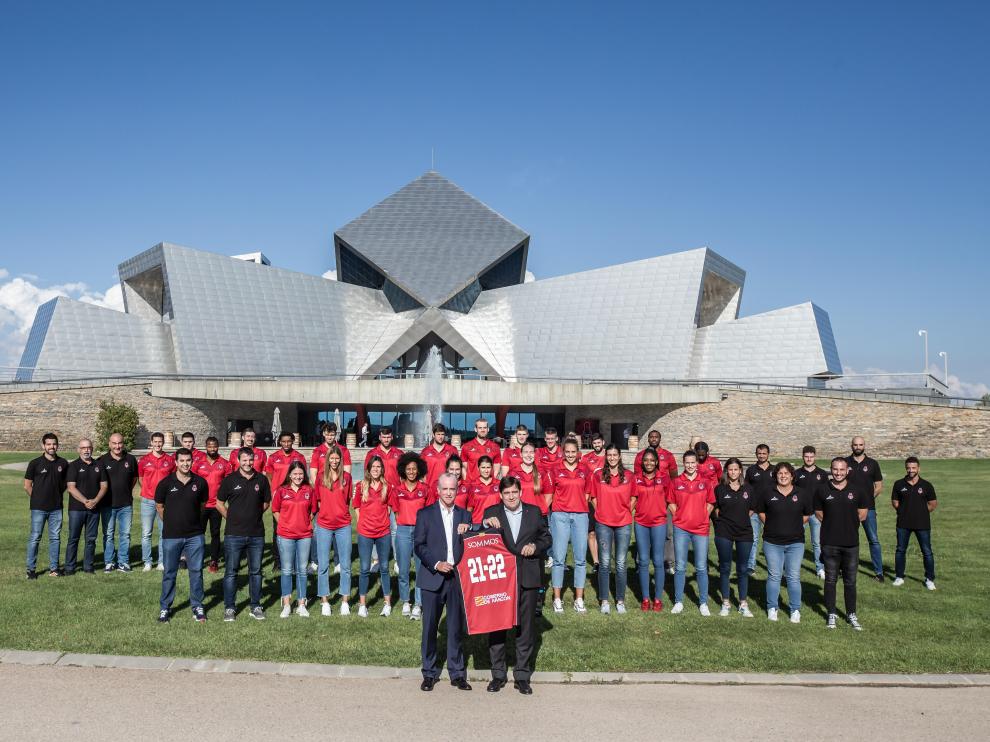 Jorge Costa y Reynaldo Benito posan con una camiseta del Casademont Zaragoza delante de las dos plantillas del club.