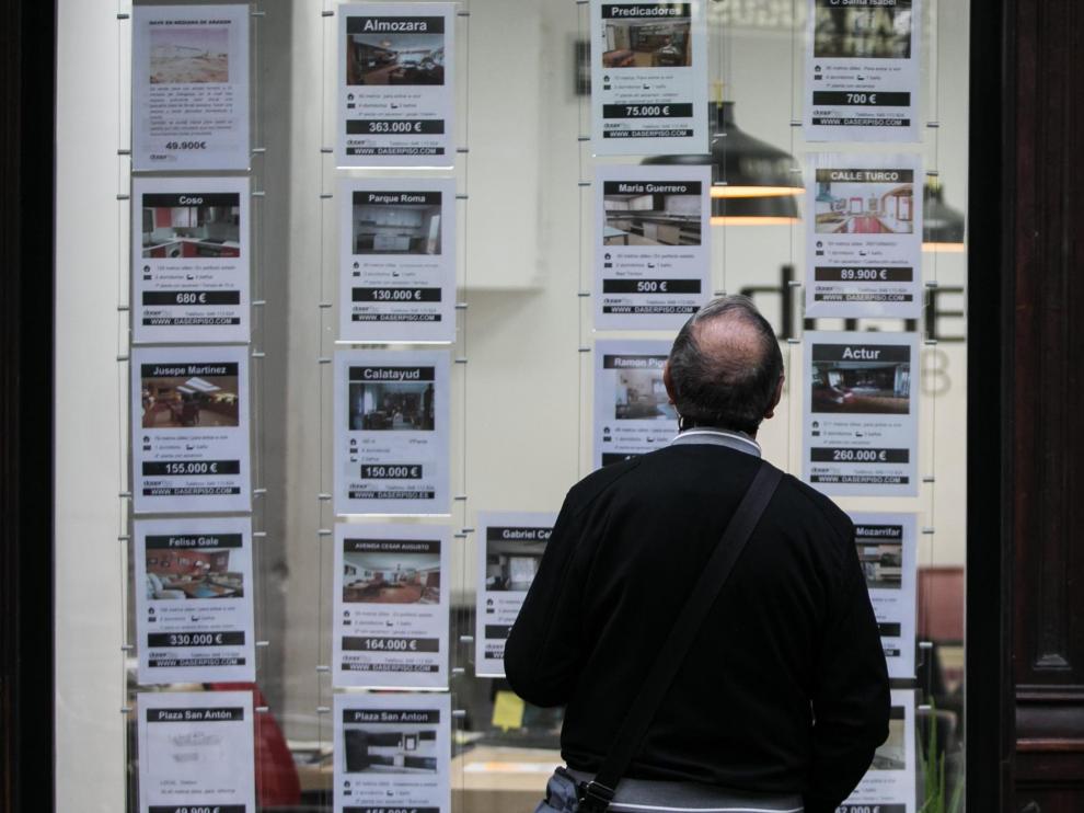 Un zaragozano mira los pisos en venta y en alquiler en el exterior de una inmobiliaria, ayer.