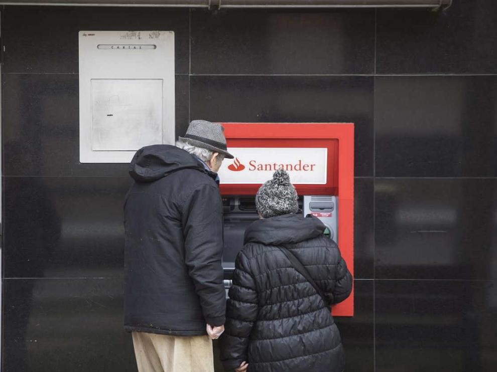 Una pareja de jubilados operan en el cajero automático de una entidad bancaria en Zaragoza.