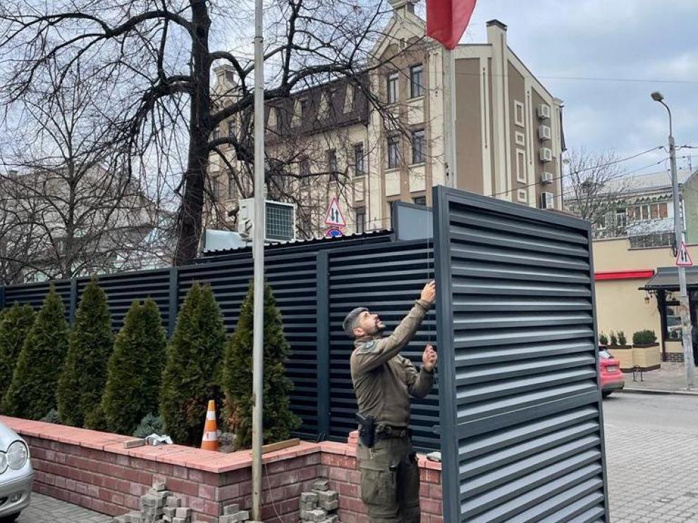Un geo retira la bandera de la Embajada de españa en Kiew (Ucrania) que ha quedado cerrada esta mañana.