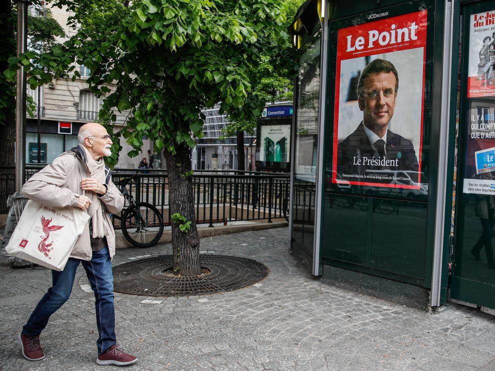 Un hombre camina junto a un kiosco en el que figura una portada del seminario Le Point, que informa de la victoria de Macron, este lunes en París.