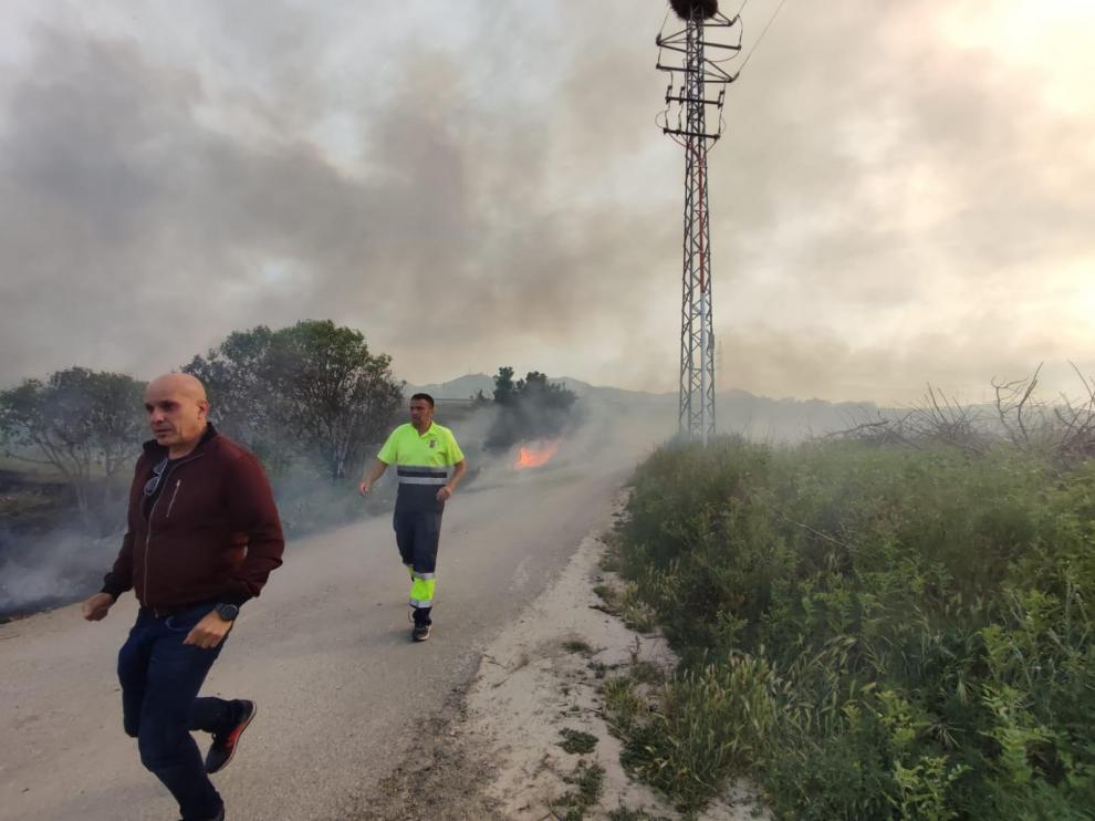 Dos vecinos de El Burgo de Ebro, pasan apresurados junto a las llamas