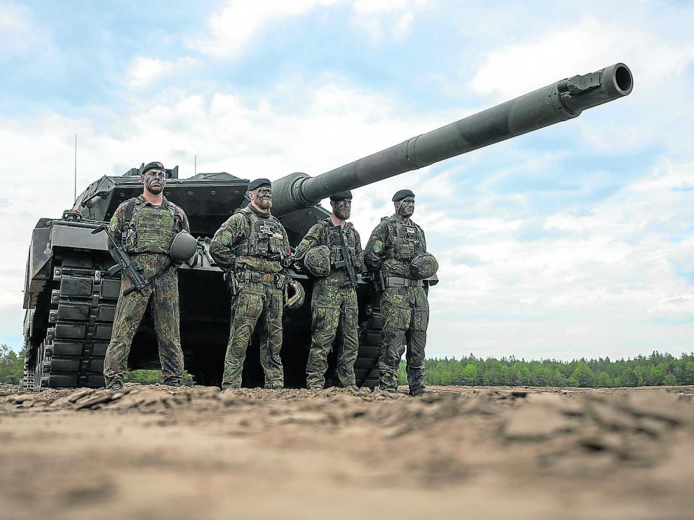 07 June 2022, Lithuania, Pabrade: Soldiers stand in front of a German Army Leopard-2 tank used by the NATO Enhanced Forward Presence Battle Group (eFP battalion) during a visit by German Chancellor Olaf Scholz to Camp Adrian Rohn. Photo: Michael Kappeler/dpa 07/06/2022 ONLY FOR USE IN SPAIN