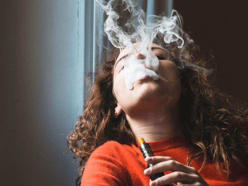 Una joven usando un cigarrillo electrónico.