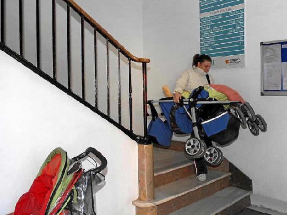Una mujer desciende por la escalera principal del centro de salud con un cochecito de bebé en brazos.