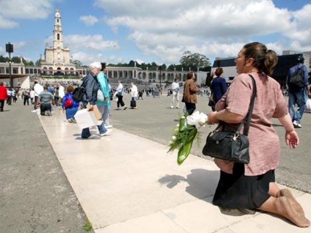 Una mujer, de rodillas frente al santuario de Fátima