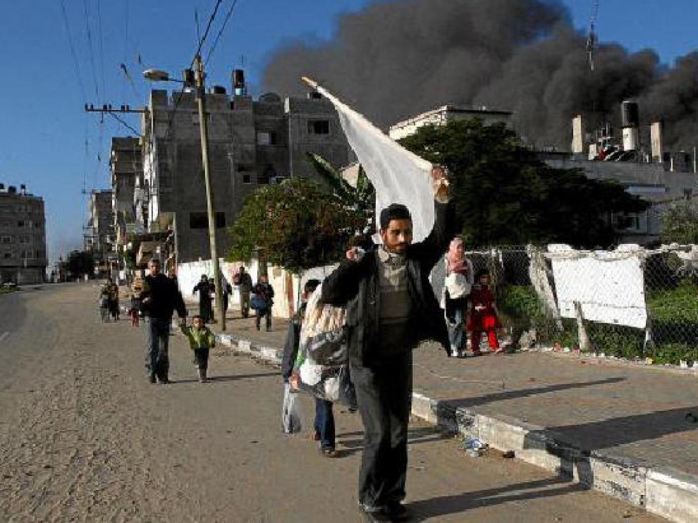Un palestino sujeta una bandera blanca al abandonar su casa en la franja de Gaza.