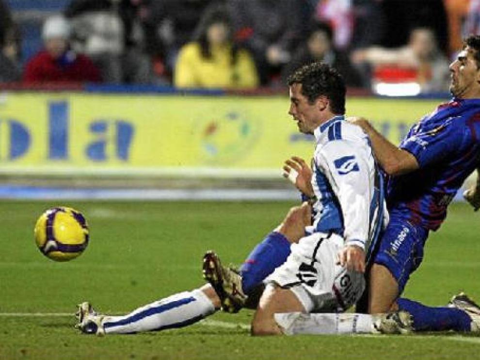 El delantero del Huesca Roberto García trata de anticiparse a un futbolista rival