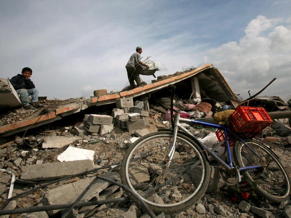 Varias personas, entre los escombros de la que fuera su vivienda, destruída durante la ofensiva israelí