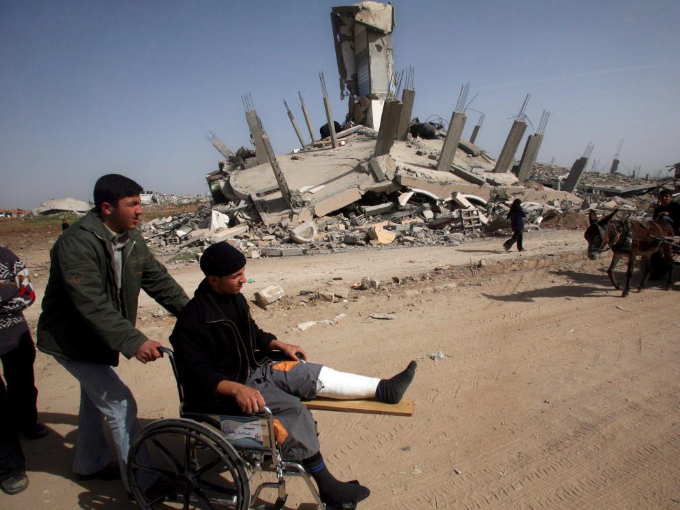 Un herido, en silla de ruedas, visita una zona de Gaza destrozada por las bombas israelíes