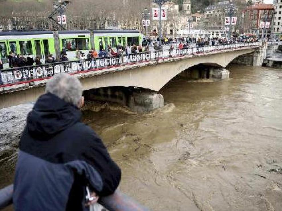 Un hombre contempla la ría del Nervión, a su paso por Bilbao, en plena crecida.