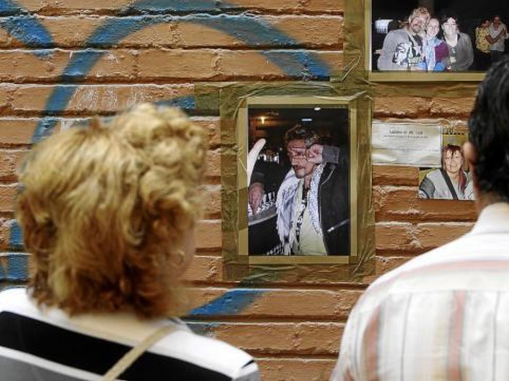 Dos vecinos de La Magdalena miran fotos de la víctima que sus amigos colocaron en su recuerdo.