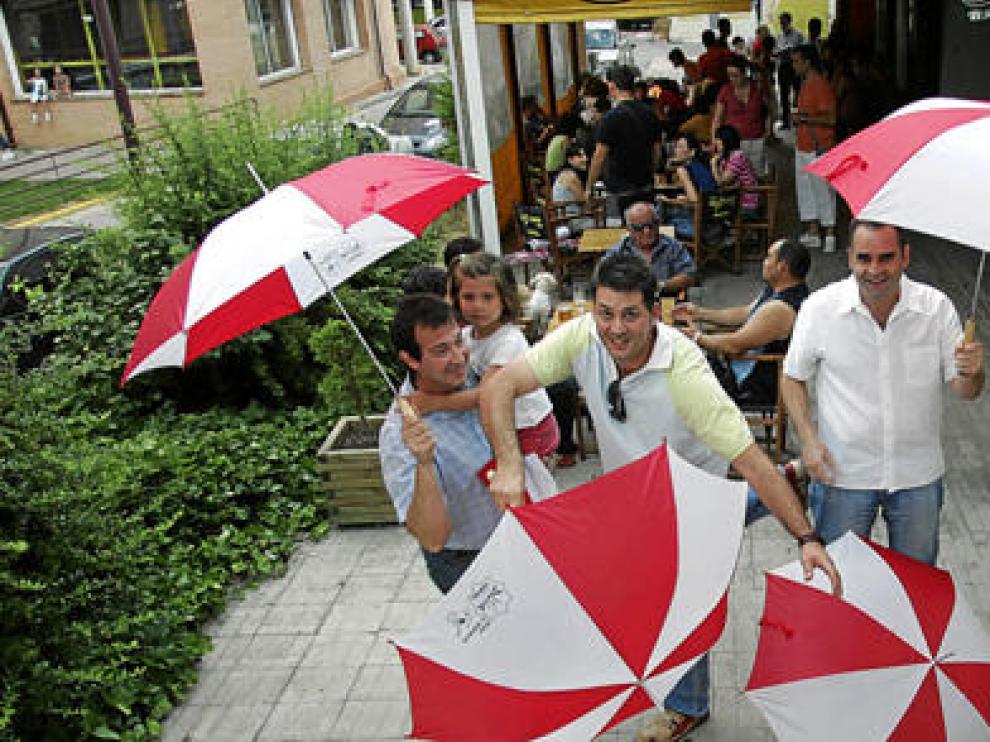 Peñistas de El Disfrute, tras recibir los vales de comidas y bebidas junto con el regalo sorpresa de esta Vaquilla, un paraguas rojiblanco