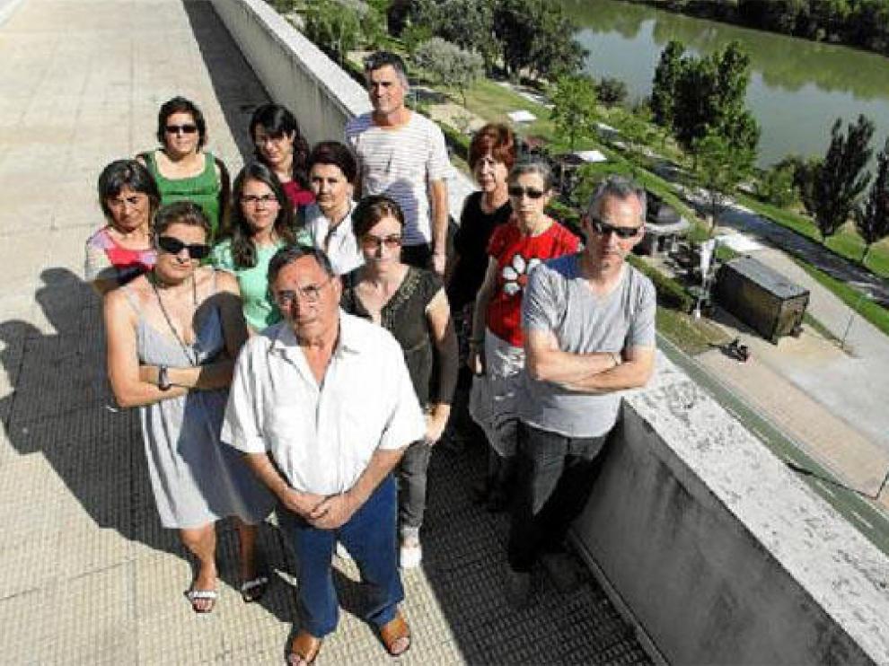 Un grupo de vecinos, en la terraza de la comunidad, con la ribera y el quiosco al fondo.
