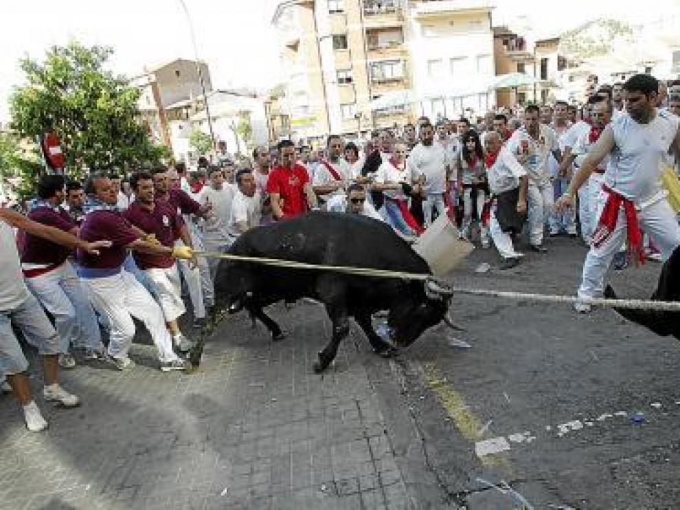 Los miembros de la Soga y Baga libran a un corredor -con camiseta verde caqui- de una cogida con un tirón de la soga.