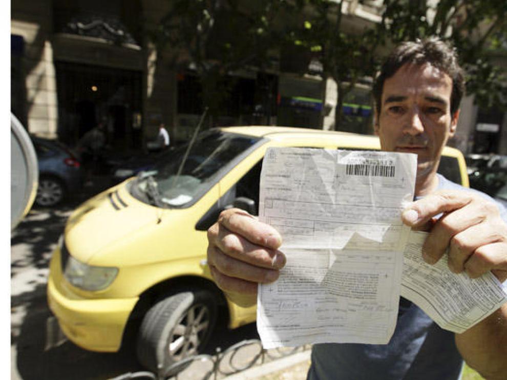 Andrés Espiño, junto a otro vehículo de su empresa, muestra la multa que le pusieron el viernes.