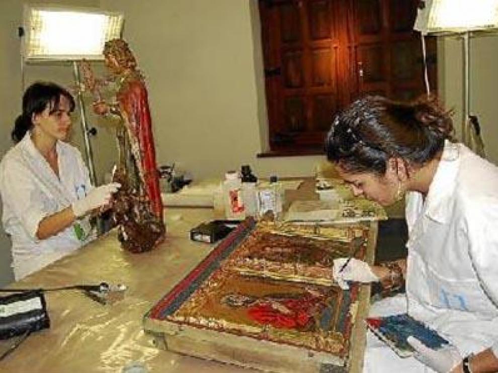 Dos restauradores, en pleno proceso de recuperación de distintas obra de pintura y escultura