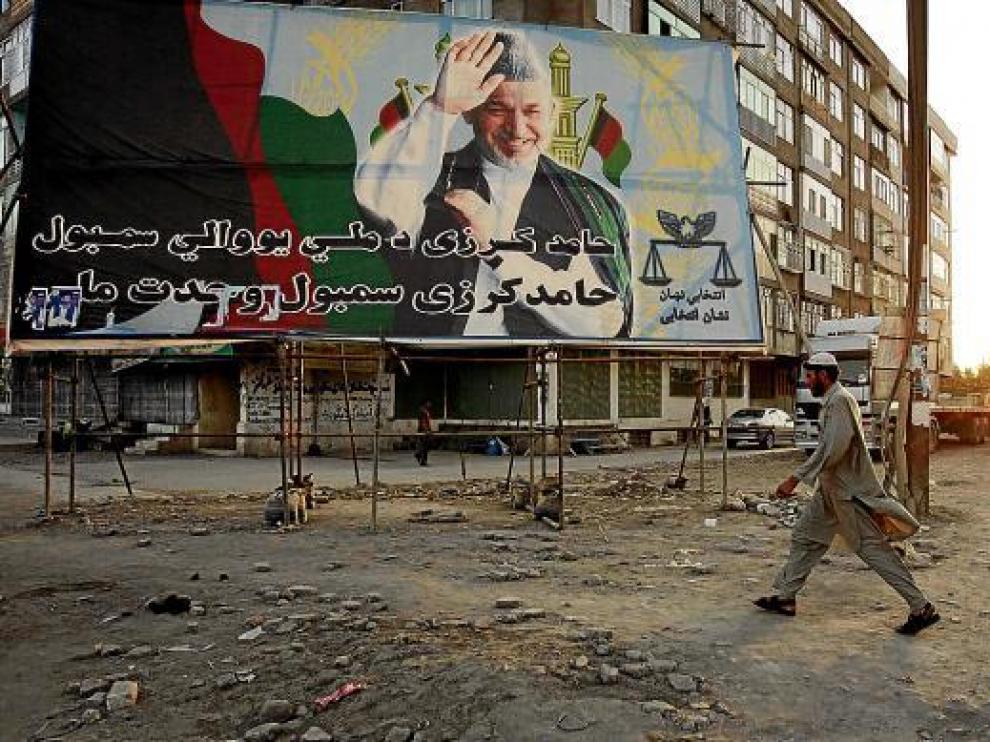 Un hombre pasa frente a un cartel electoral del presidente afgano Karzai, en Kabul.