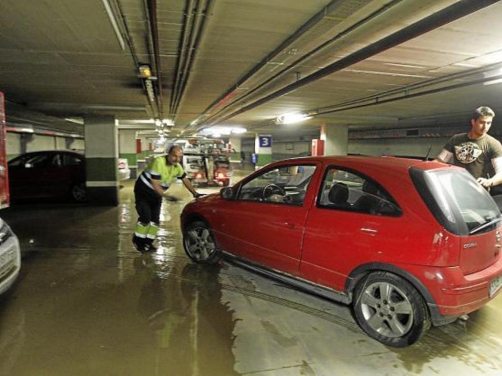 Una grúa retira del aparcamiento uno de los vehículos afectados por la inundación.
