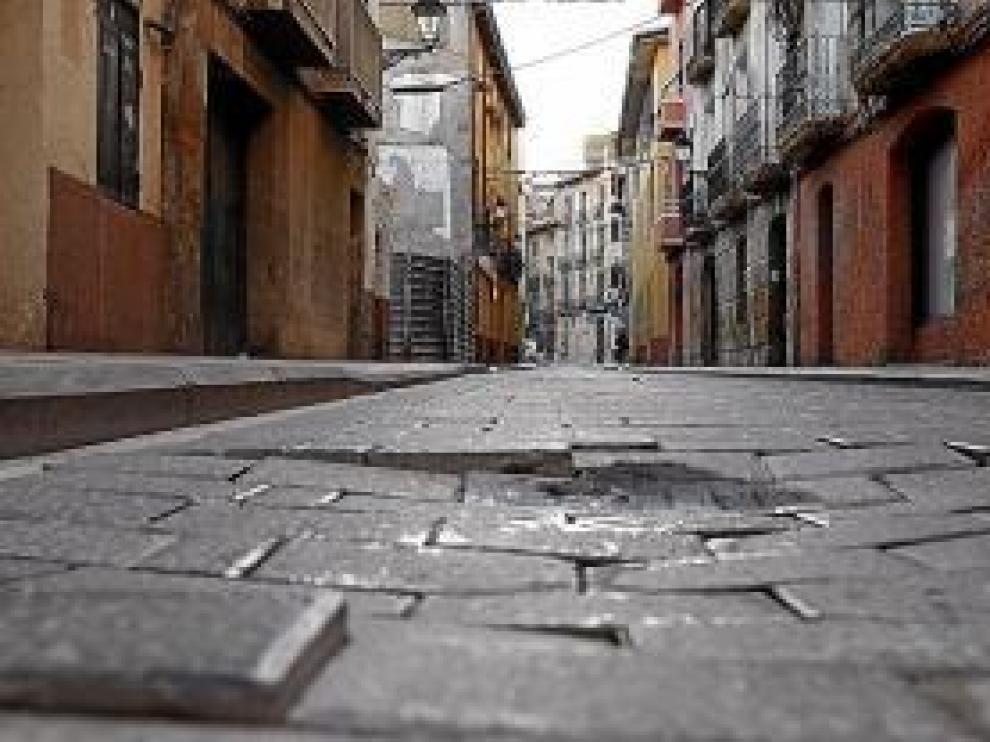 Los agujeros y desniveles de los adoquines suponen un problema para los vehículos, los peatones y los comerciantes de la zona, que han denunciado la situación.