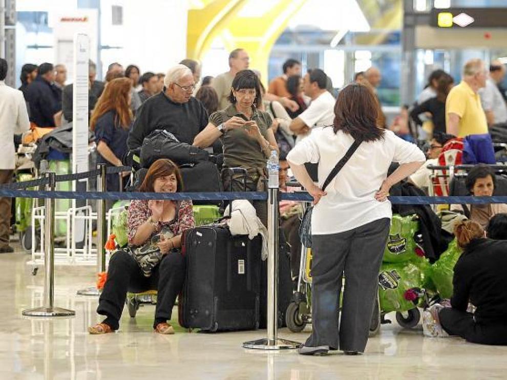 Varios pasajeros esperan conocer su vuelo, ayer en la T-4 del aeropuerto de Barajas.