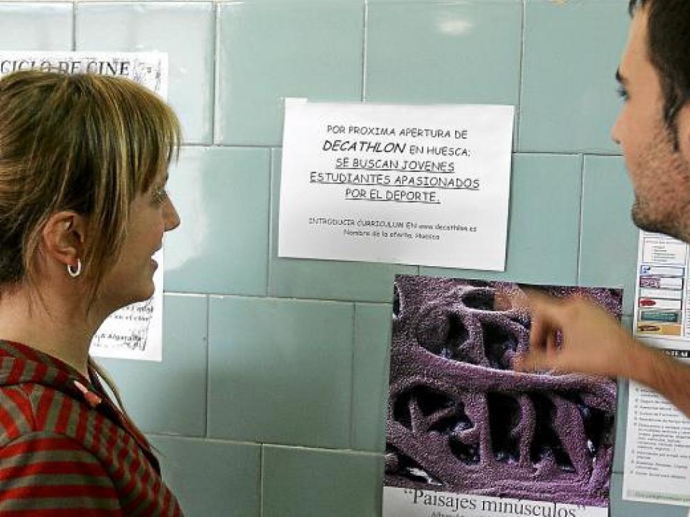 Dos estudiantes miran el cartel de Decathlon en la facultad de C.C. Humanas y de la Educación.