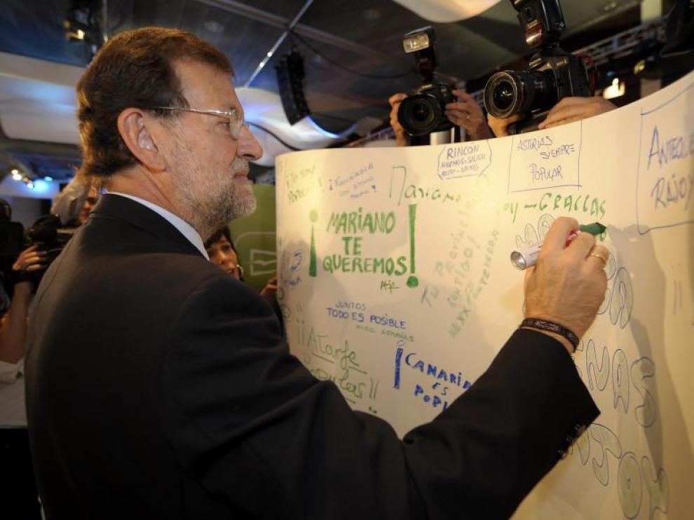 Rajoy escribe en un panel colocado en la sala donde se celebra la convención nacional del PP.