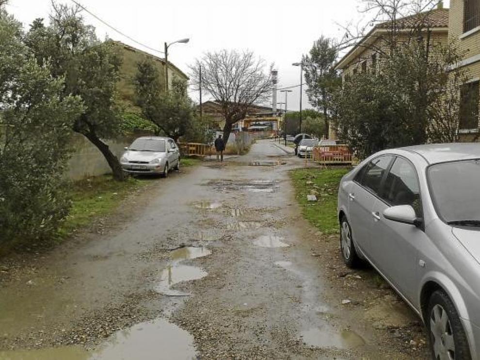 La calle El Greco aparece llena de charcos y barro cuando llueve