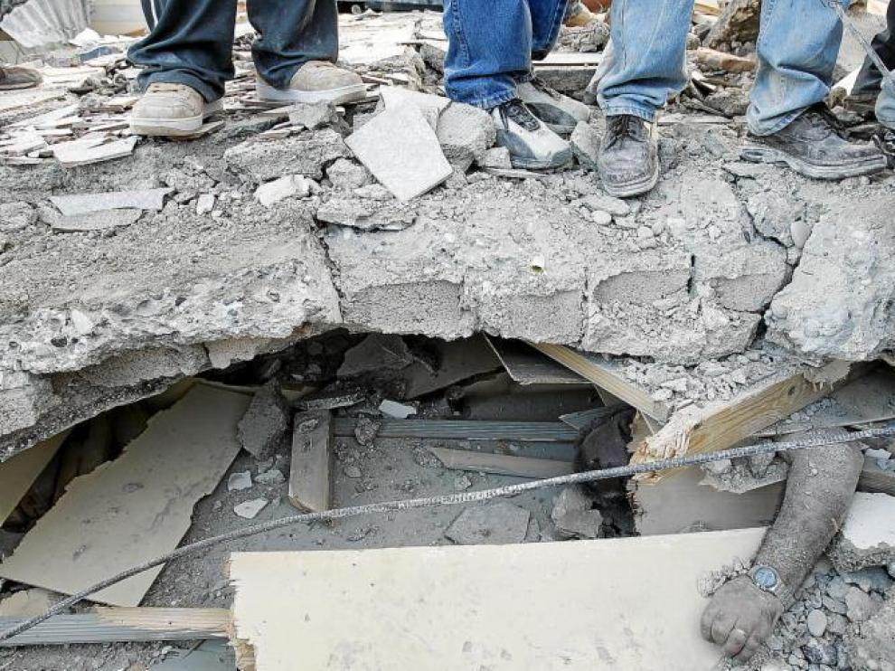El brazo de un hombre sepultado aparece bajo los escombros de una construcción en Puerto Príncipe.