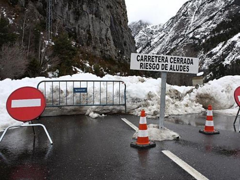 Un cartel, una valla y varias señales alertan del cierre de la carretera al balneario de Panticosa.
