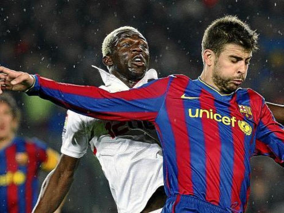 Piqué pugna con el sevillista Koné por el esférico.
