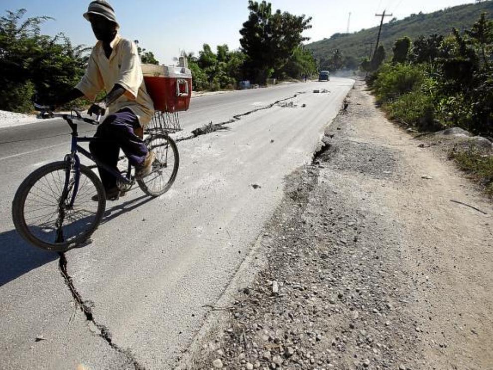 Un hombre pasa en bicicleta por una carretera agrietada a las afueras de Leogane, el viernes