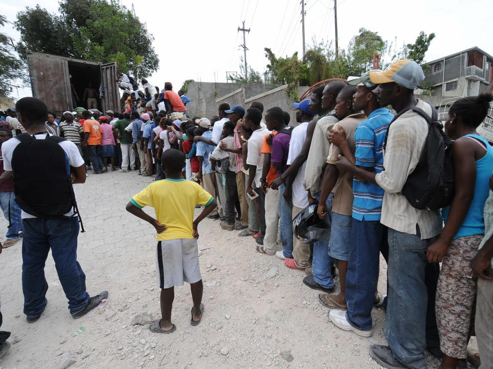 Varios ciudadanos haitianos hacen cola para recibir la ayuda humanitaria