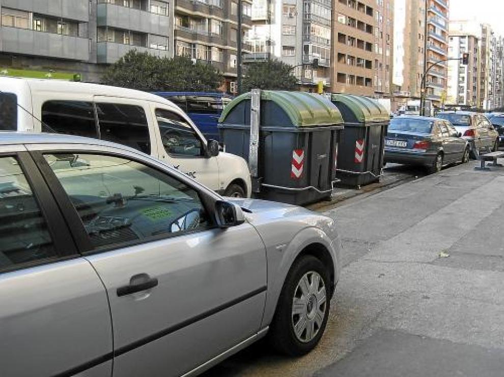 Contenedores y coches aparcados en el carril derecho e, incluso, sobre la acera, en la avenida de Navarra.