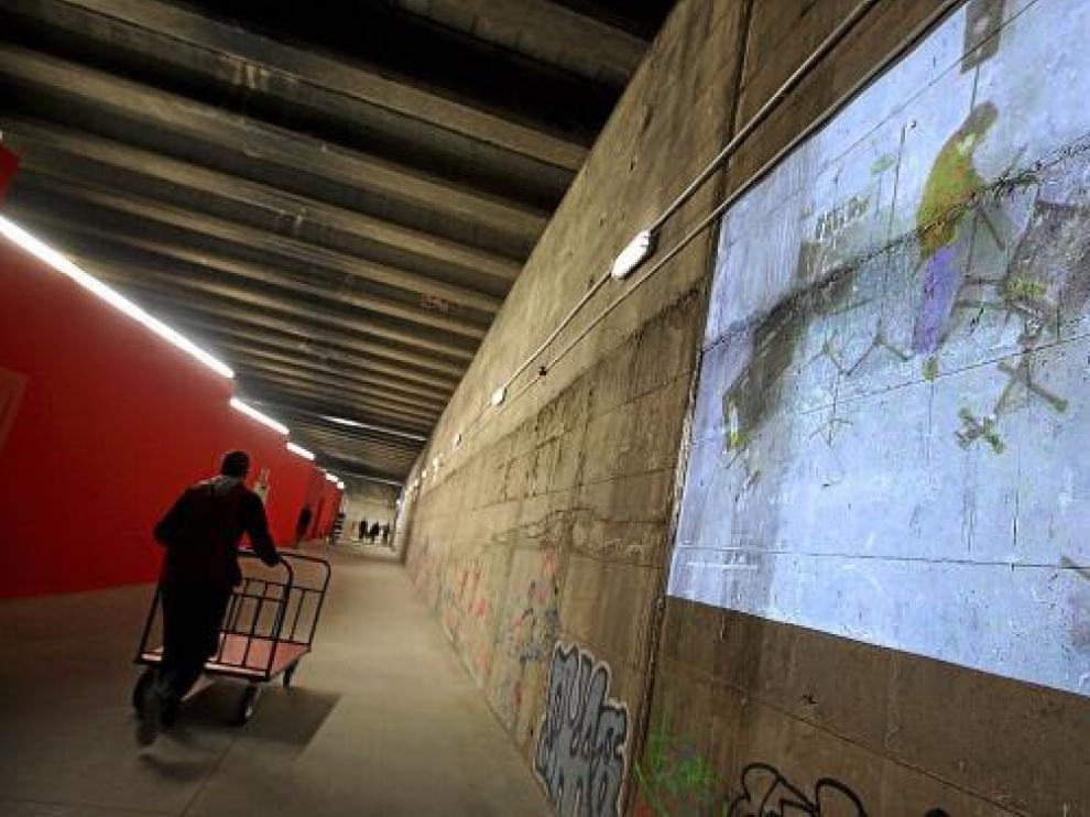 El pasadizo central, con grafitis e imágenes de proyectores, por donde antes discurrían las vías.