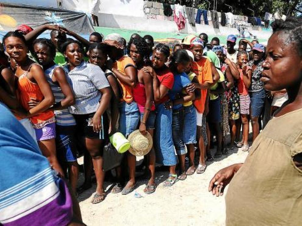 Una embarazada, frente a las mujeres que esperan la distribución de agua, en Puerto Príncipe