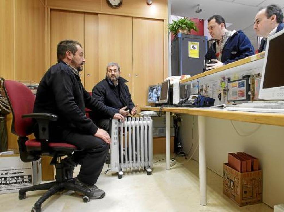 Dos oficiales se calientan con un calefactor en la recepción del centro cívico.