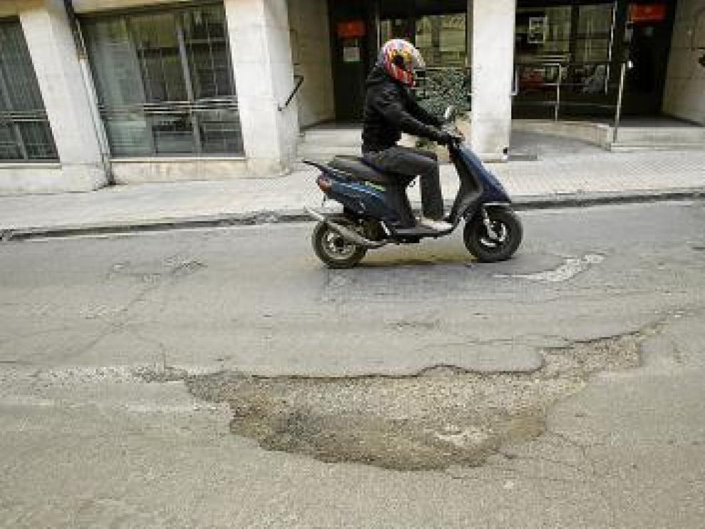 Un motorista sortea un bache en la calle Joaquín Arnau.