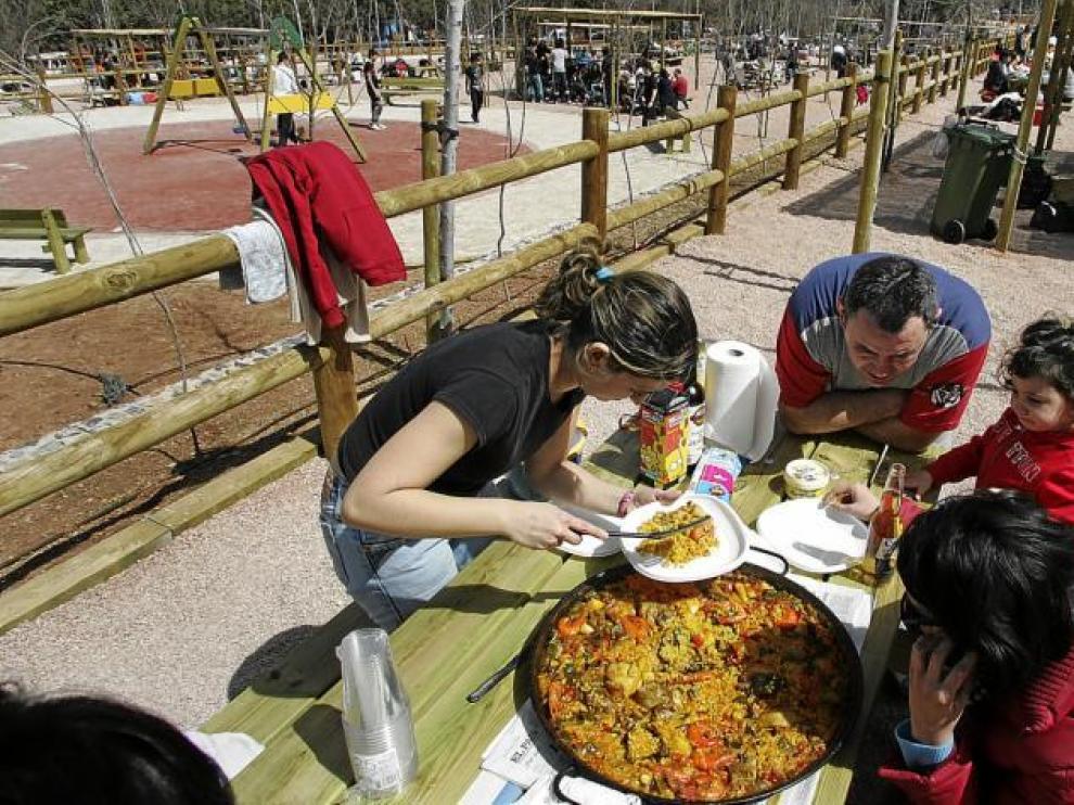 Un grupo de excursionistas se dispone a comer una paella en el nuevo parque de Fuentecerrada, con todas las mesas ocupadas.