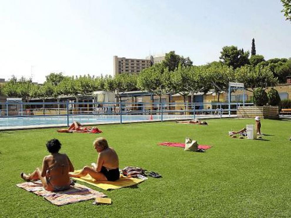 Varias usuarias de una piscina municipal tomando el sol.