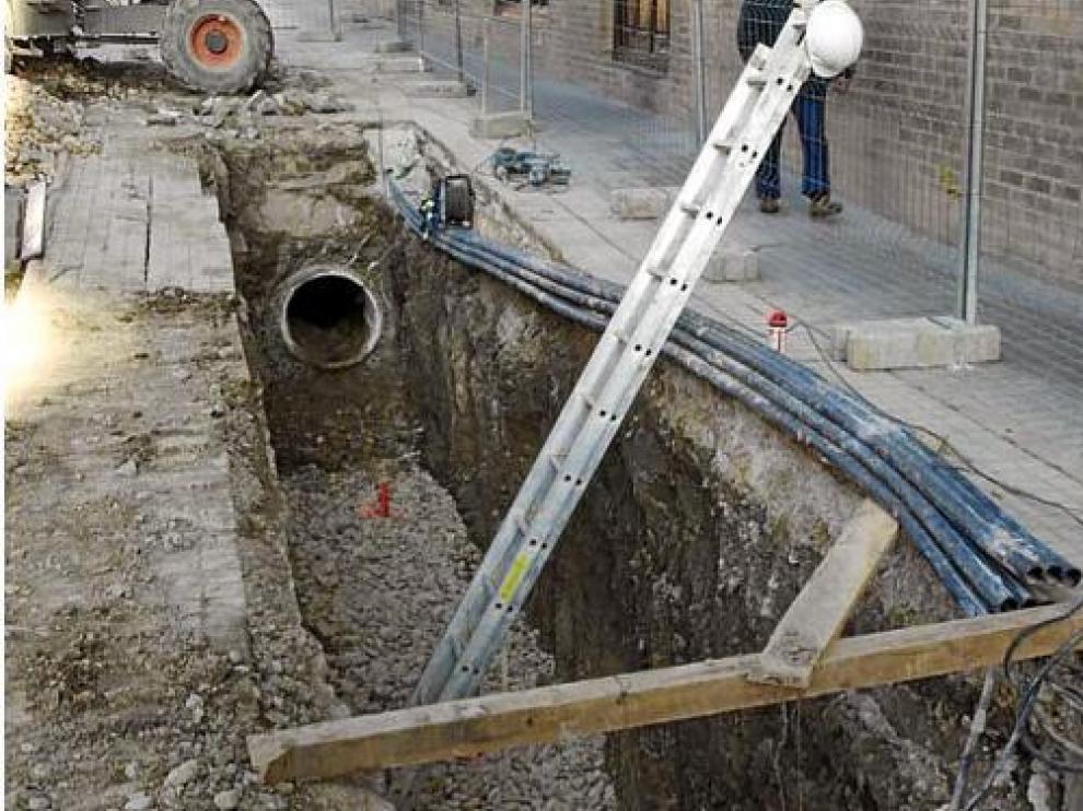 Sobre estas líneas, la zanja abierta en la travesía de Zavacequias. Al lado, una raíz de casi 4 metros hallada en el interior del colector.