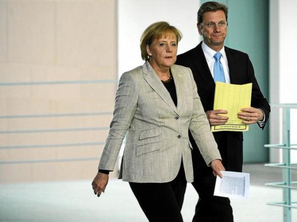 Angela Merkel, acompañada por el ministro alemán de Exteriores, camino de una rueda de prensa, ayer en Berlín.