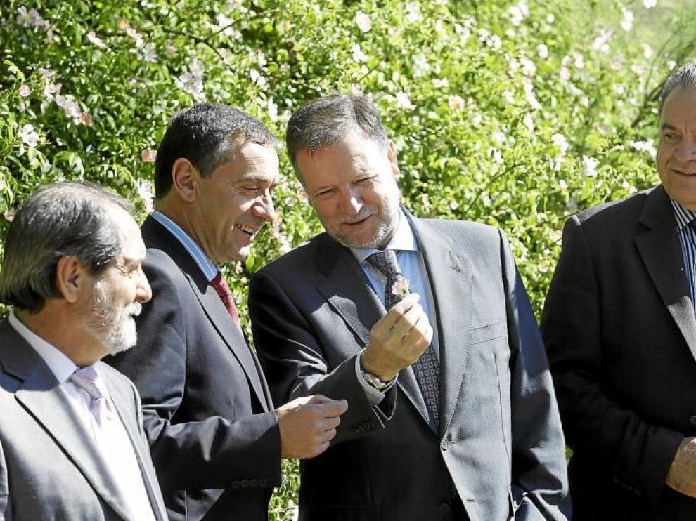 El presidente Iglesias bromea con el secretario de Estado y le muestra una flor, ante la atenta mirada de los consejeros Velasco y Boné.