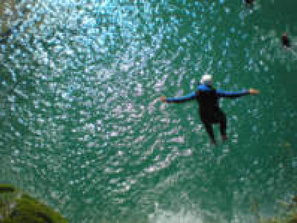 Un barranquista se lanza al agua en un barranco de la Sierra de Guara
