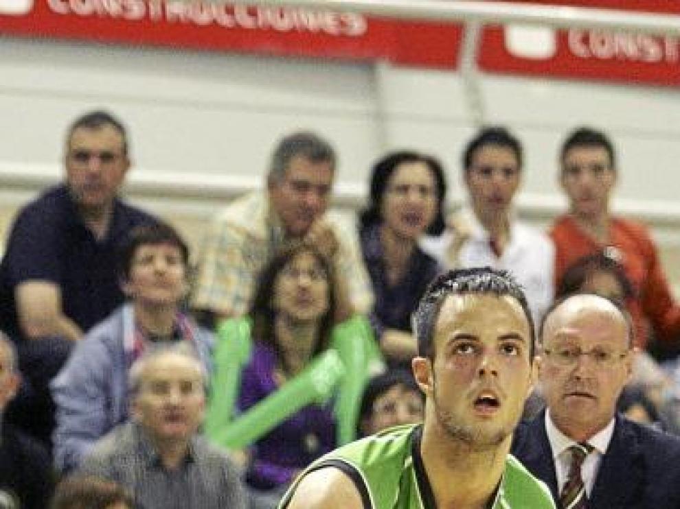 Asier prepara el triple bajo la atenta mirada de Navarro.