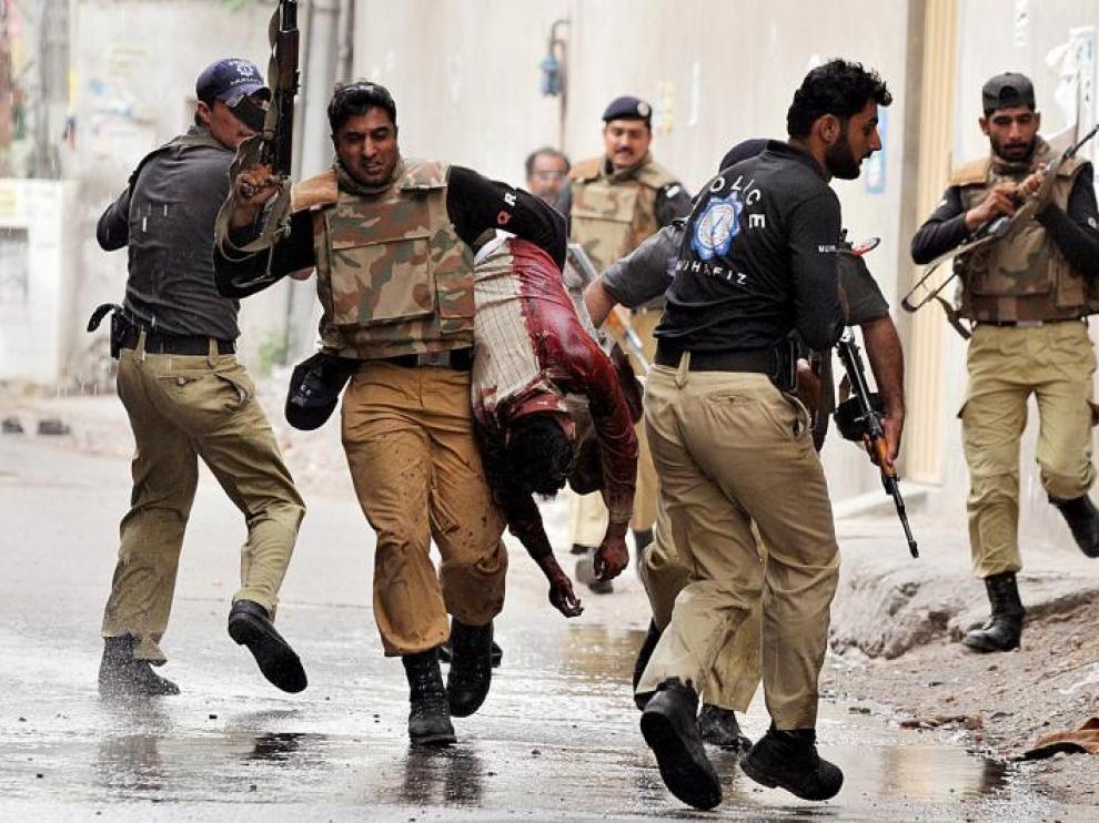 Agentes pakistaníes protegen una de las mezquitas atacadas en Lahore y llevan a un herido, ayer.