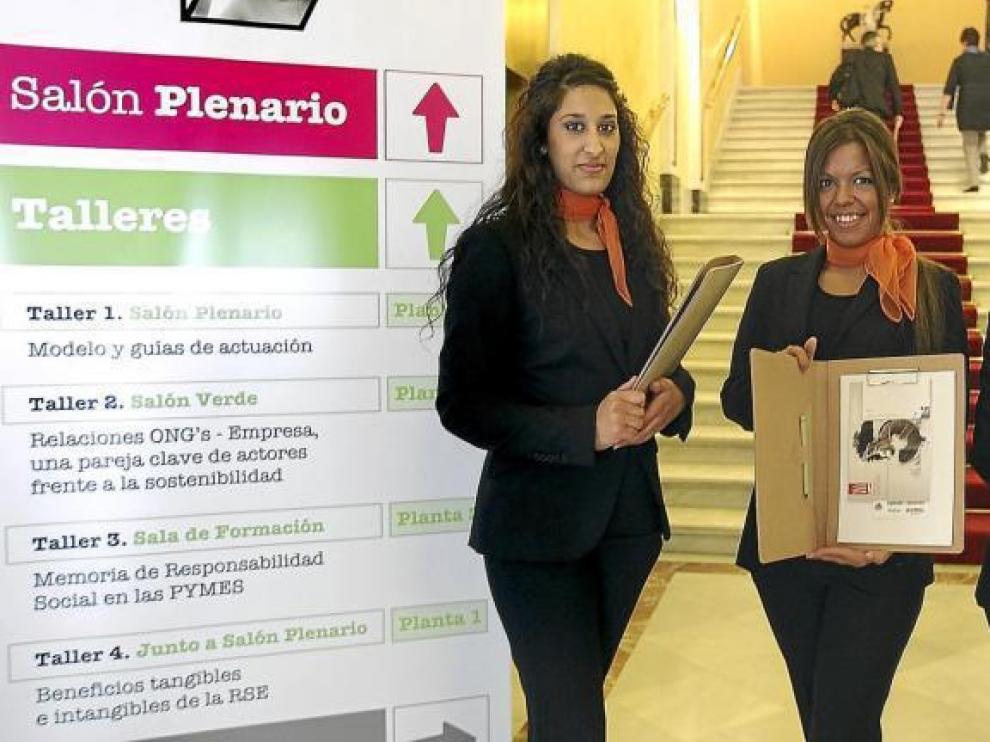 El personal auxiliar del congreso muestra el material reciclado que se dio a todos los ponentes, en la apertura del encuentro.